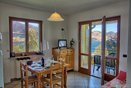 Großansicht des Zimmers mit Küchenzeile und großen Fenstertüren, die auf den Balkon führen