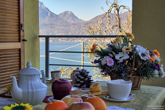 Detail der Frühstückstisch auf der Balkon und der Gardasee im Hintergrund