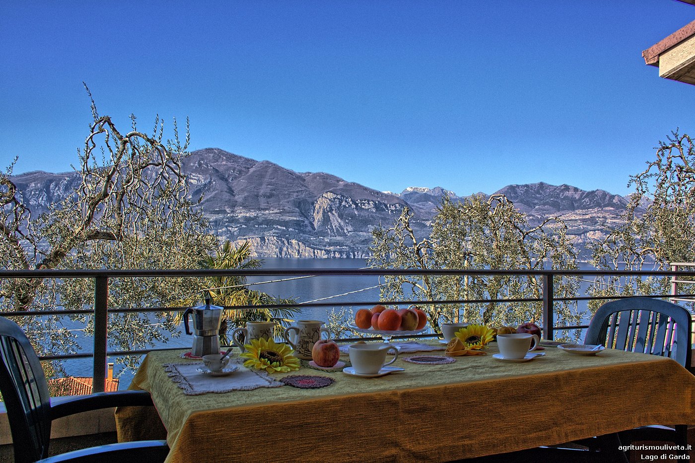 Auf der Terrasse mit Blick auf den Garten und den ruhigen See an einem schönen, sonnigen Frühlingsmorgen ist der Tisch für das Frühstück gedeckt.