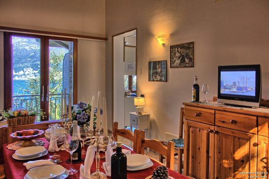 Detail auf dem Tisch und im Hintergrund der Blick auf den See aus dem Fenster