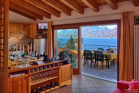 Blick auf das Zimmer mit Tisch und Kochecke und großer Fenstertür zum Balkon