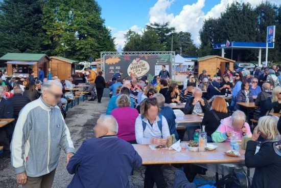 Gruppen von Besuchern, die am Tisch sitzen, während des Kastanienfestes von San Zeno di Montagna